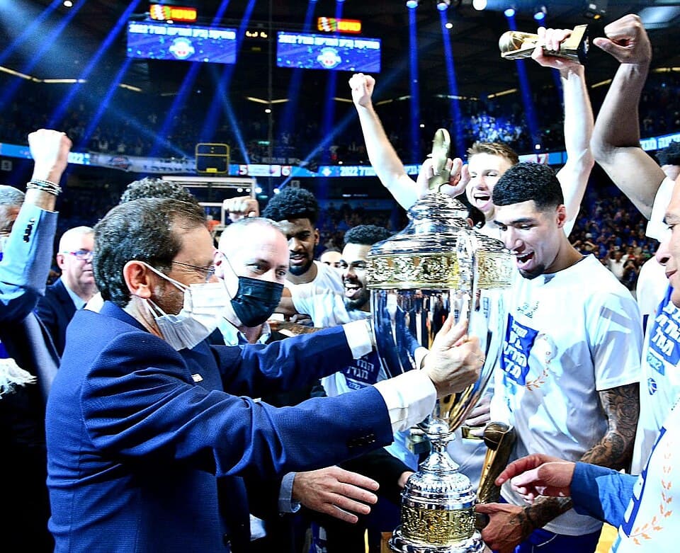 The President of Israel , Isaac Herzog , awards the State Basketball Cup to Bnei Herzliya, after winning the final match between Bnei Herzliya and Hapoel Tel Aviv at Menora Mivtach